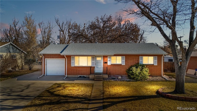 ranch-style house with brick siding, fence, concrete driveway, a lawn, and a garage