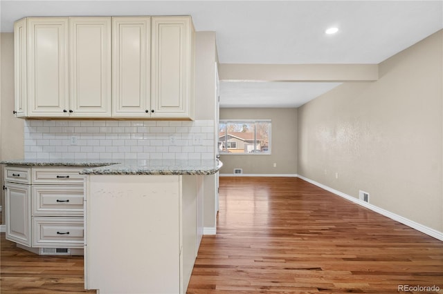 kitchen featuring light wood-type flooring, decorative backsplash, and visible vents