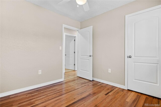 unfurnished bedroom featuring a ceiling fan, light wood-type flooring, and baseboards