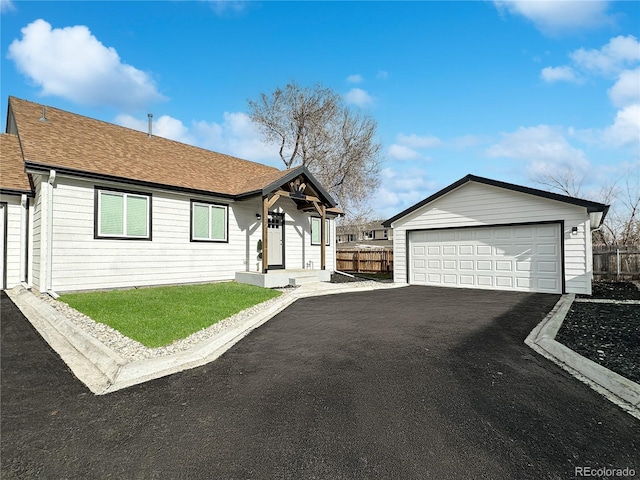 view of front of house featuring a garage, roof with shingles, an outdoor structure, and fence