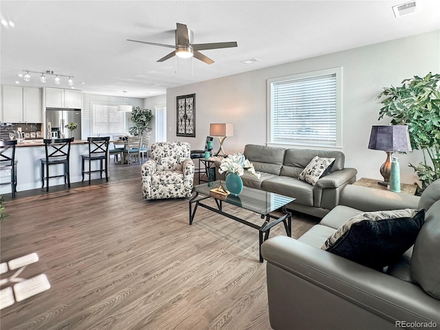 living room featuring visible vents, plenty of natural light, ceiling fan, and wood finished floors