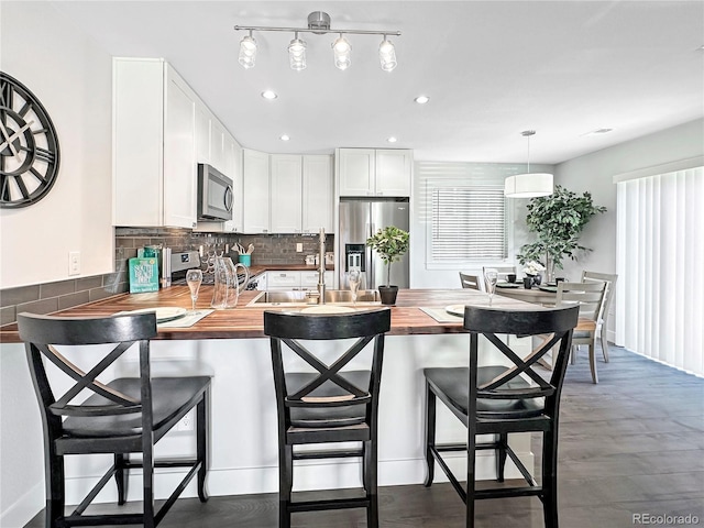 kitchen featuring kitchen peninsula, wooden counters, white cabinetry, and stainless steel appliances