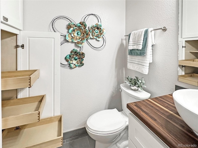 bathroom featuring a sink, toilet, and a textured wall