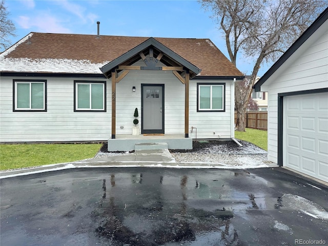 view of front of property featuring a garage, roof with shingles, and fence