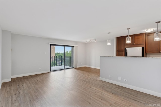 480 S Marion Pkwy Unit 802, Denver, CO 80209 - unfurnished living room featuring light wood finished floors, baseboards, and rail lighting