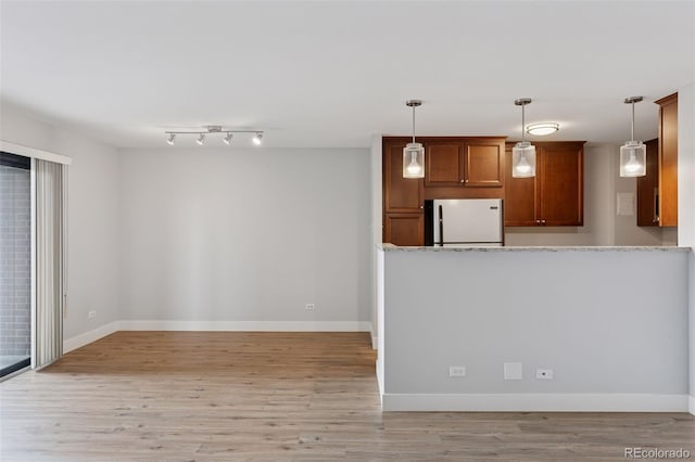 480 S Marion Pkwy Unit 802, Denver, CO 80209 - kitchen featuring freestanding refrigerator, light wood-style floors, brown cabinetry, pendant lighting, and baseboards