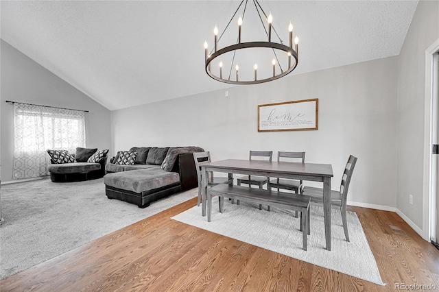 dining area featuring hardwood / wood-style floors, lofted ceiling, and a notable chandelier