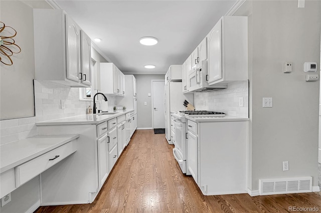 kitchen featuring tasteful backsplash, sink, white cabinets, and white appliances