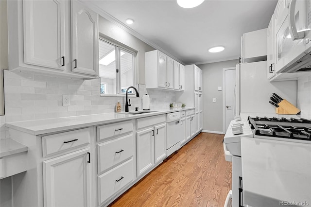 kitchen with backsplash, white appliances, sink, light hardwood / wood-style flooring, and white cabinetry