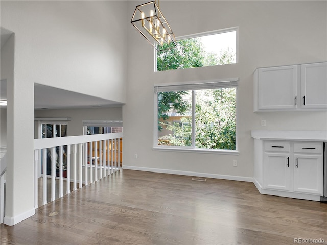 1288 S Beeler Ct, Denver, CO 80247 - unfurnished dining area with a towering ceiling, a chandelier, and wood finished floors