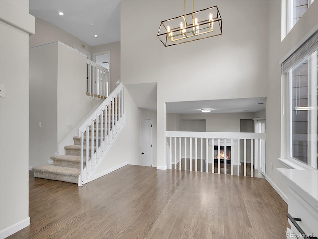 1288 S Beeler Ct, Denver, CO 80247 - unfurnished living room with a high ceiling, wood finished floors, stairs, a chandelier, and a glass covered fireplace