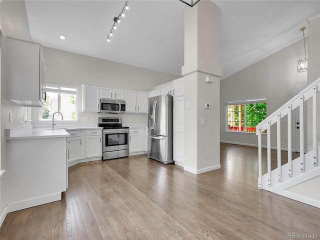 1288 S Beeler Ct, Denver, CO 80247 - kitchen with stainless steel appliances, light countertops, white cabinets, light wood-style floors, and rail lighting