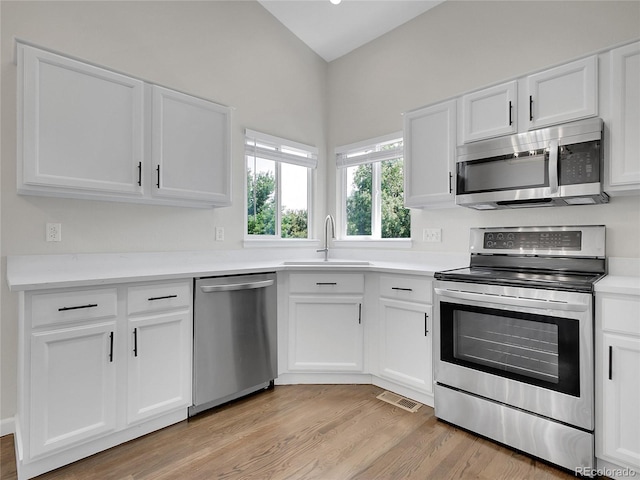 1288 S Beeler Ct, Denver, CO 80247 - kitchen featuring appliances with stainless steel finishes, light wood-type flooring, white cabinets, and light countertops