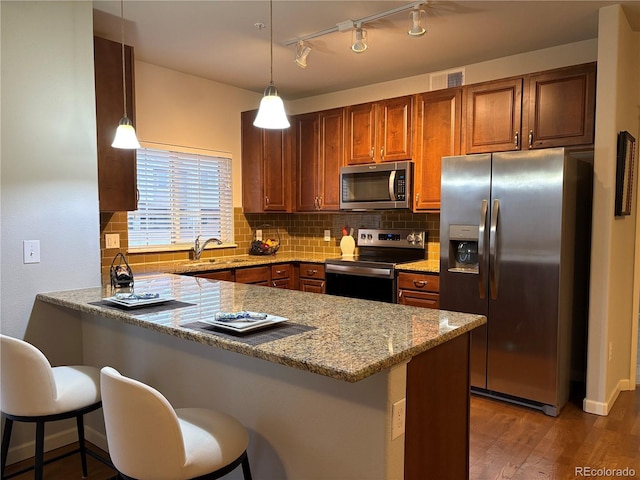 kitchen featuring a peninsula, a sink, visible vents, appliances with stainless steel finishes, and decorative backsplash