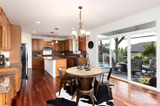 dining area featuring rail lighting, dark hardwood / wood-style flooring, sink, and a chandelier