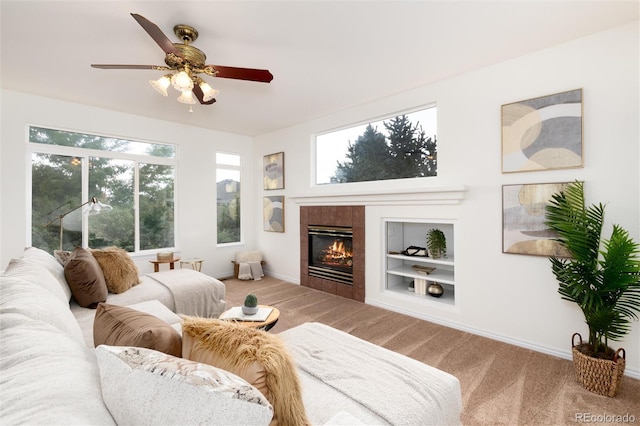 carpeted living room with ceiling fan, a fireplace, and built in features