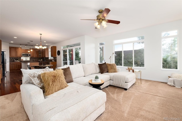 living room featuring light carpet and ceiling fan with notable chandelier