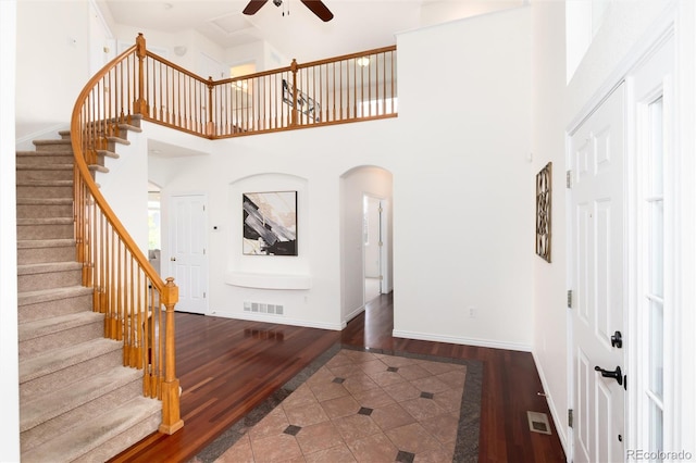 entryway featuring ceiling fan, dark tile patterned flooring, and a high ceiling