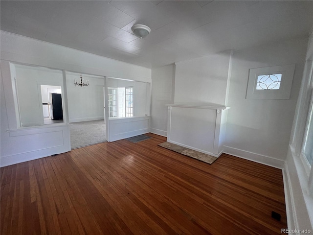 unfurnished living room with dark wood-type flooring and a notable chandelier