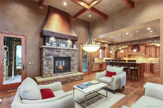 living room with hardwood / wood-style flooring, a high ceiling, a fireplace, and beam ceiling