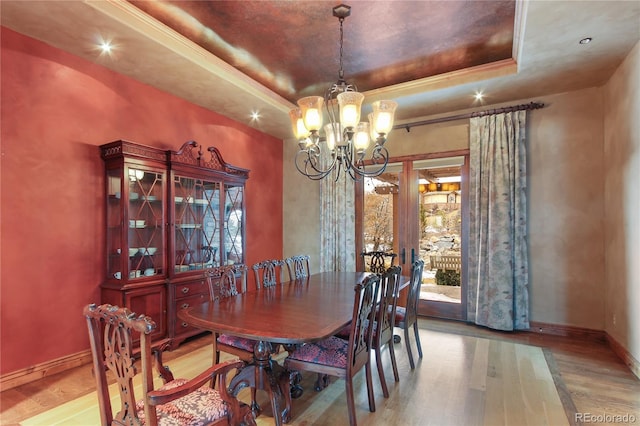 dining area with wood-type flooring, a notable chandelier, a raised ceiling, crown molding, and french doors