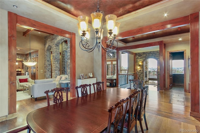 dining space featuring a tray ceiling, beam ceiling, wood-type flooring, and a chandelier