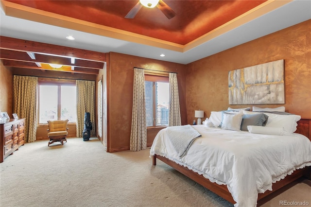 bedroom featuring ceiling fan, a raised ceiling, carpet, and multiple windows