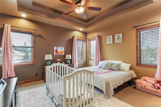 bedroom featuring light carpet and a tray ceiling