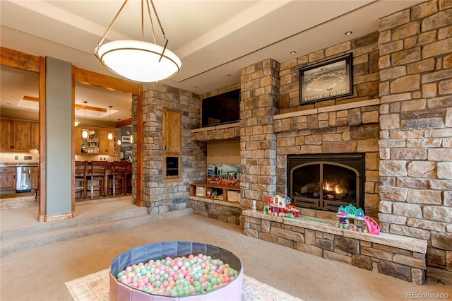 carpeted living room featuring a stone fireplace and a raised ceiling