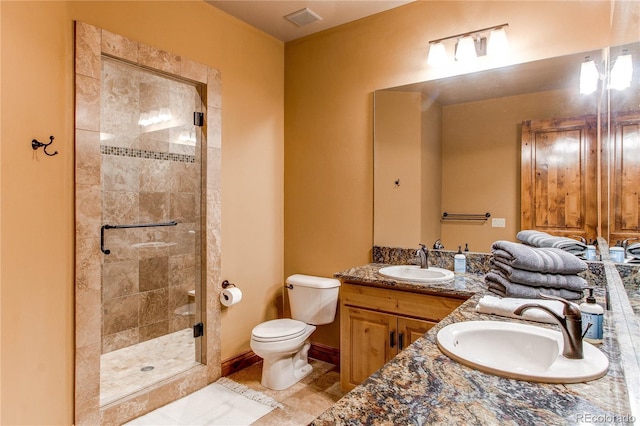 bathroom featuring vanity, a shower with shower door, and toilet