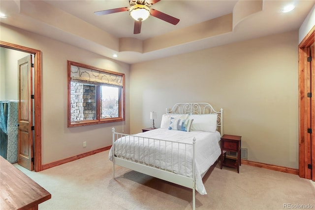 carpeted bedroom featuring a tray ceiling and ceiling fan