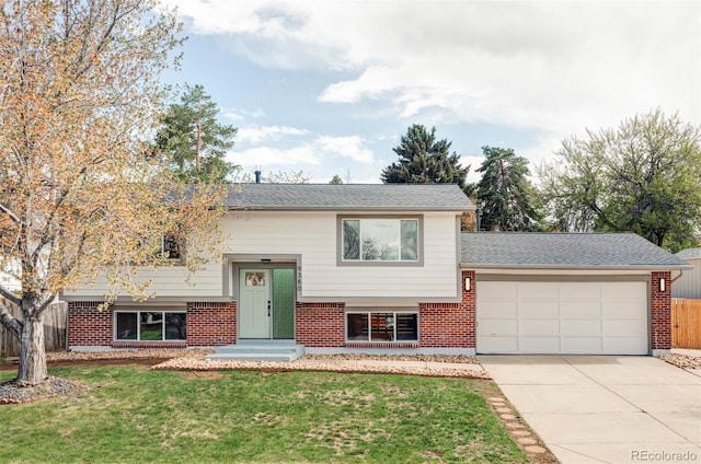 raised ranch featuring an attached garage, driveway, and brick siding