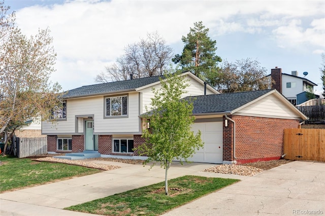 raised ranch featuring brick siding, fence, a garage, concrete driveway, and roof with shingles