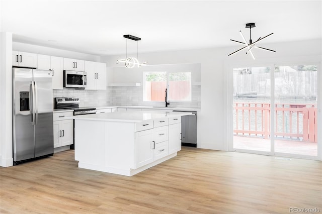 kitchen with stainless steel appliances, a chandelier, light wood-style flooring, light countertops, and backsplash
