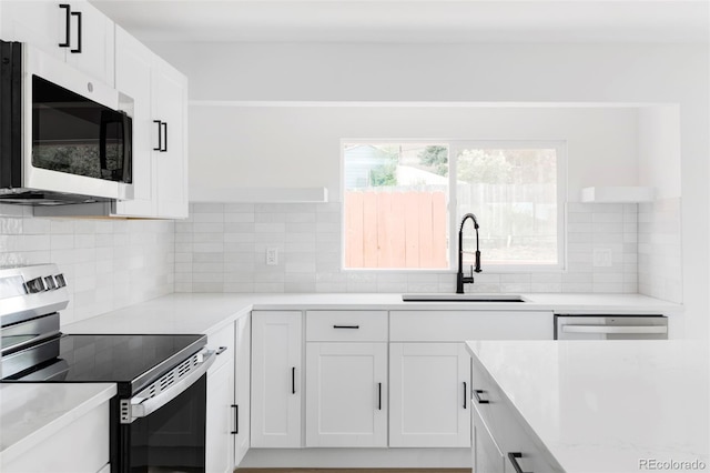 kitchen featuring appliances with stainless steel finishes, a sink, open shelves, and white cabinetry