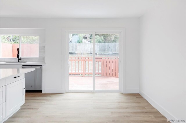 kitchen with a sink, dishwasher, white cabinets, and healthy amount of natural light