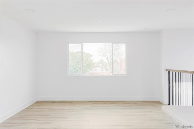 empty room featuring light wood-style floors, baseboards, and recessed lighting