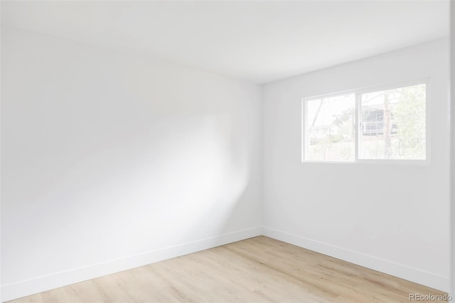 unfurnished room with baseboards and light wood-style floors