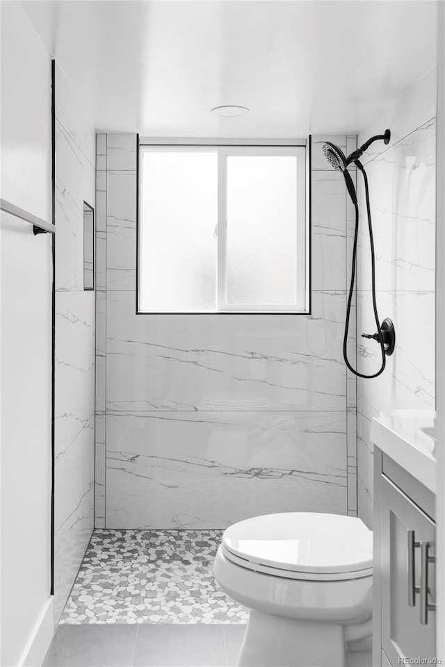 bathroom with toilet, a marble finish shower, and tile patterned floors