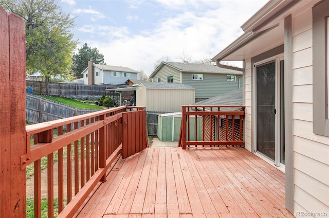 wooden terrace with a storage shed, a fenced backyard, and an outdoor structure