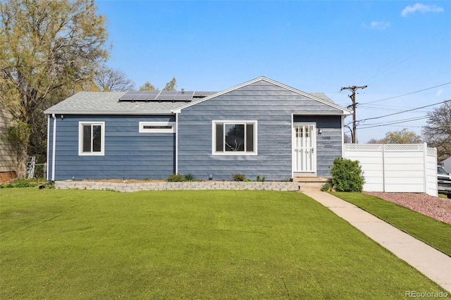 single story home with a front yard and roof mounted solar panels