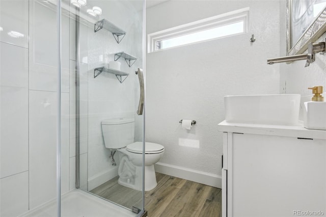 bathroom featuring vanity, toilet, wood finished floors, and a stall shower