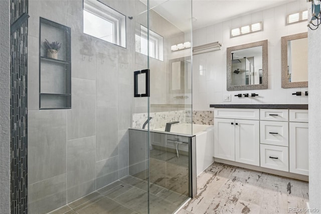 full bathroom with tile walls, vanity, and a stall shower