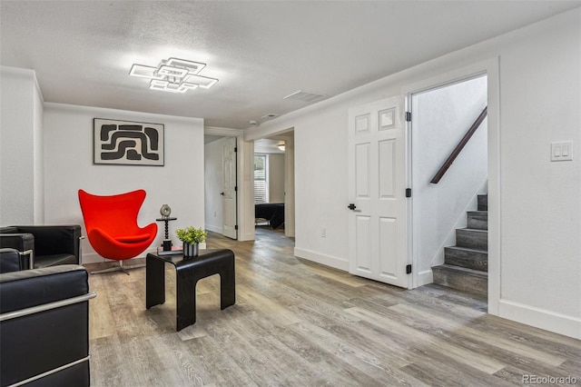 living room featuring stairway, wood finished floors, baseboards, and visible vents