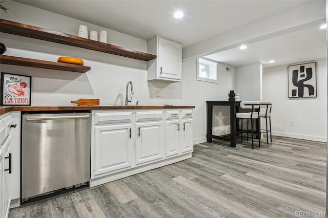 kitchen with stainless steel dishwasher, a sink, white cabinetry, open shelves, and light wood-style floors