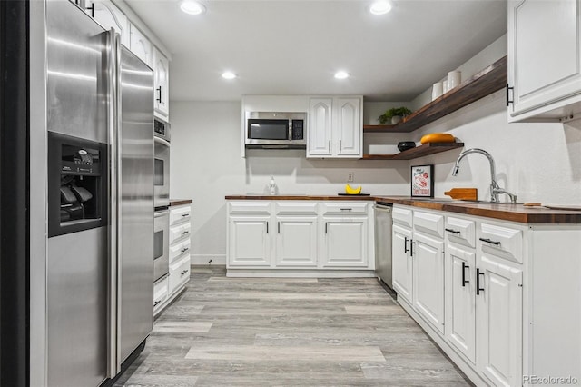 kitchen with a sink, open shelves, wood counters, appliances with stainless steel finishes, and recessed lighting