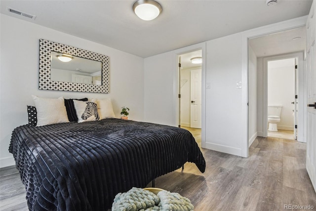 bedroom featuring baseboards, visible vents, and wood finished floors