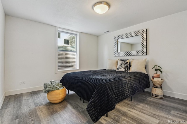 bedroom with baseboards, visible vents, and wood finished floors