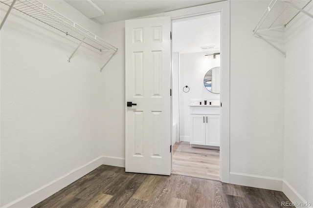 walk in closet with dark wood-style flooring and a sink
