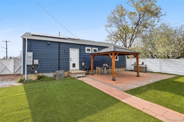 back of property featuring roof mounted solar panels, a gazebo, a lawn, and a fenced backyard